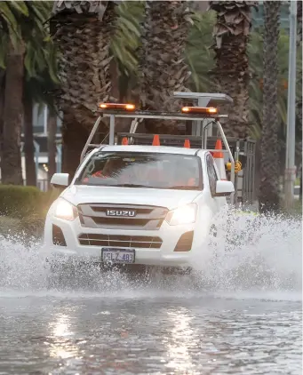  ?? EPA ?? A lorry crosses floodwater by the Swan River in the north of Perth, Western Australia, where thousands of homes and businesses were left without power after heavy rain