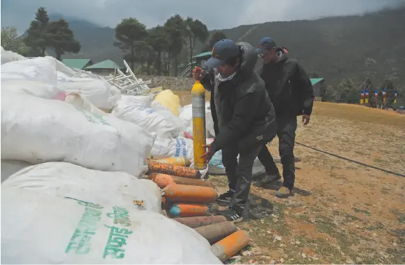  ?? AP PHOTO BY NIRANJAN SHRESTHA ?? Members of garbage retrieval expedition pile up empty oxygen cylinders collected from Mount Everest in Namche Bajar, Solukhumbu district, Nepal on May 27. The record number of climbers on Mount Everest this season has left a cleanup crew grappling with how to clear away everything from abandoned tents to human waste that threatens drinking water.