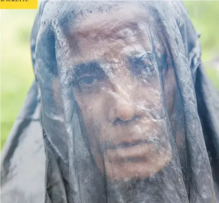  ?? DAR YASIN / THE ASSOCIATED PRESS ?? A Rohingya refugee waits in the rain near the Balukhali refugee camp in Bangladesh. More than 410,000 Rohingya have crossed the border.