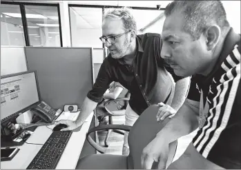  ?? JOHN GIBBINS/SAN DIEGO UNION-TRIBUNE PHOTOS ?? Jason Heil, left, co-owner of the Redial call center in Tijuana and supervisor Joaquin Aviles discuss call volume.