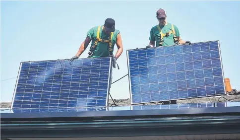  ?? — WP-Bloomberg photo by Michael Nagle ?? SolarCity Corp. employees install solar panels on the roof of a home in Kendall Park, New Jersey, on July 28, 2015.