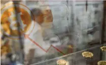  ?? — AFP ?? A man walks past a display cabinet containing models of bitcoins in Hong Kong.