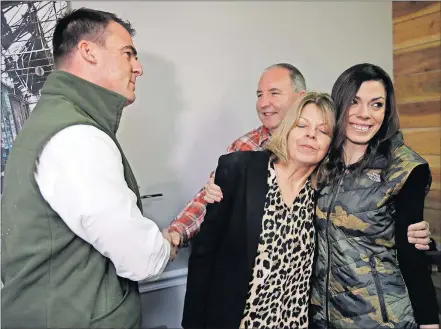  ?? [MIKE SIMONS/ TULSA WORLD] ?? Gov. Kevin Stitt, left, shakes hands Thursday with Steve Bear as Bear's wife, Rhonda Bear, hugs her daughter, Sara Williams. Stitt had just signed a pardon for Rhonda Bear at She Brews Coffee House in Claremore.