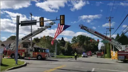  ?? DAVE SCHLOTT - DIGITAL FIRST MEDIA ?? A flag is suspended from two ladder trucks earlier this week as the body of longtime Crozer-Chester Medical Center EMS boss Robert Reeder arrives at a funeral home in Brookhaven.