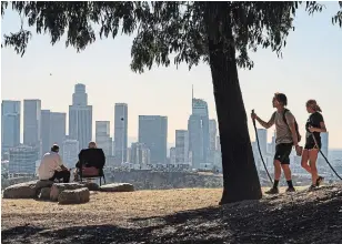  ?? DAMIAN DOVARGANES THE ASSOCIATED PRESS ?? Albert Maghbouleh, far left, and Miles Santamour share a socially distanced lunch outdoors while overlookin­g the skyline of Los Angeles on Monday.