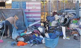  ?? GREGORY BULL ASSOCIATED PRESS ?? A woman who was camping in downtown San Diego sorts through her belongings on a sidewalk that was being sprayed with a bleach solution to fight a deadly hepatitis A outbreak.