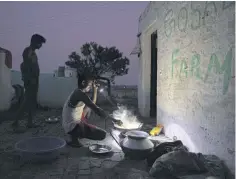 ??  ?? Bijay Kumar, a migrant worker from Bihar, uses a flashlight to prepare a meal.