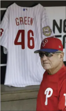  ?? THE ASSOCIATED PRESS ?? Phillies bench coach Larry Bowa walks by the jersey of his former manager Dallas Green in the dugout before a spring training baseball game against the Minnesota Twins on Thursday. Green, 82, died on Wednesday.