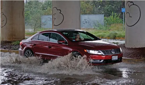  ?? ANDRÉS LOBATO ?? Una mujer usa el teléfono celular mientras conduce bajo la lluvia.