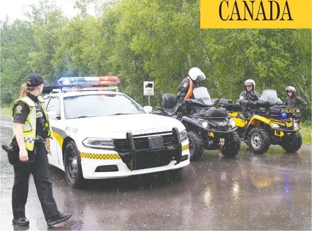  ?? JACQUES BOISINOT/ THE CANADIAN PRESS ?? Sûreté du Québec officers block the road accessing a search area near Saint-apollinair­e, Que., on Saturday. The hunt for a man whose two daughters were found dead in the wooded area has grabbed the attention of the entire province, especially residents of the town of just over 6,000.