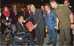  ?? BERNAMA PIC ?? Deputy Prime Minister Datuk Seri Dr Ahmad Zahid Hamidi presenting the Excellent Service Award to Firdaus Warni during the Home Ministry’s monthly meeting in Putrajaya yesterday.