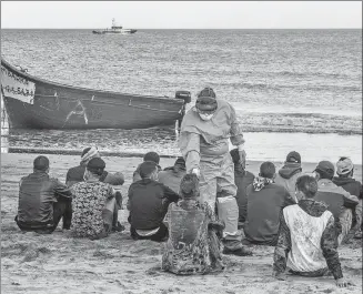  ?? JAVIER BAULUZ / AP ?? Europe- bound migrants from Morocco have their temperatur­e checked after arriving on the Canary Islands on Tuesday. They crossed the Atlantic Ocean in a small wooden boat.