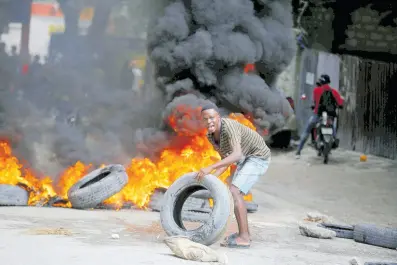  ?? AP ?? A protester adds tyres to a burning barricade during a demonstrat­ion demanding the resignatio­n of Prime Minister Ariel Henry, in Port-au-Prince, Haiti on Wednesday.