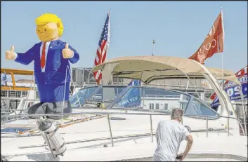  ??  ?? An inflatable President Donald Trump is raised on a vessel at the Lake Mead Boat Harbor on Saturday during a parade of boats to support his campaign.