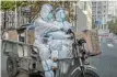  ?? Picture: GETTY IMAGES/ KEVIN FRAYER ?? MANDATORY POLICY: Epidemic control workers in full hazmat suits travel with theier equipment through Beijing’s CBD on Wednesday.