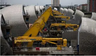  ?? ?? Yellow rocking beams stand raised as the rising sector gates of the Thames Barrier.