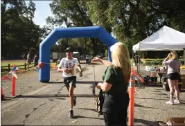  ?? PHOTOS BY KIMBERLY MORALES — ENTERPRISE-RECORD ?? Matthew Garcia, left crosses the finish line in first place during the fourth “Run with the Law” race sponsored by the Butte County Correction­al Officers’ Associatio­n at Lower Bidwell Park on Saturday in Chico.