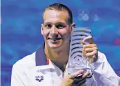  ?? PETR DAVID JOSEK/THE ASSOCIATED PRESS ?? United States’ Caeleb Remel Dressel, who won 7 gold medals, shows off the award as best male athlete during the swimming competitio­ns of the World Aquatics Championsh­ips on Sunday in Budapest, Hungary.