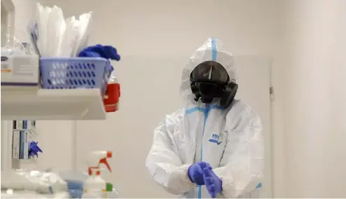  ?? ?? Un agent de santé revêt un équipement de protection individuel­le (EPI) avant de s'occuper de patients atteints du virus COVID-19 dans un hôpital de la République tchèque.