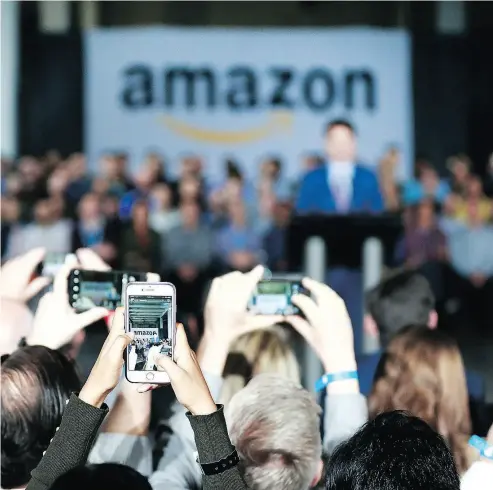  ?? JEFF VINNICK / GETTY IMAGES ?? Employees take photos as Prime Minister Justin Trudeau announces a new Amazon headquarte­rs expected to create 3,000 jobs in Vancouver. Amazon already has a large presence in Canada, employing more than 6,000 people.