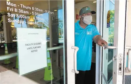  ?? JOE CAVARETTA/SOUTH FLORIDA SUN SENTINEL ?? A Pompano Beach Parks and Recreation employee looks out at the parking lot of the E. Pat Larkins Community Center on Tuesday. The center was scheduled to open for vaccinatio­ns but has been delayed.