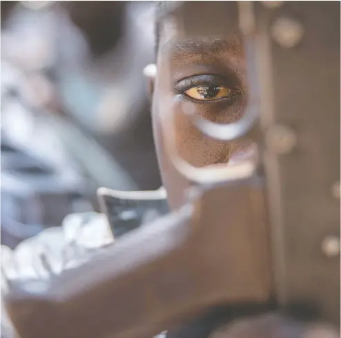  ?? STEFANIE GLINSKI / AFP / Gett y Imag es files ?? A child soldier looks through a rifle trigger guard at a 2018 release ceremony for child soldiers in South Sudan.