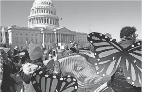  ?? JACQUELYN MARTIN/AP ?? Wearing “butterfly wings,” DACA supporters hold a tarp with an image of President Trump as they march on Capitol Hill on Monday.