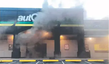  ??  ?? Smoke pours from a door at the Autobarn on Greenway Drive in Tweed Heads South.