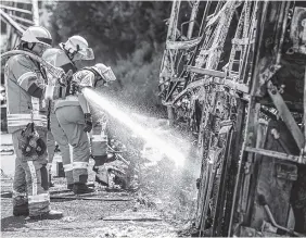  ?? THE ASSOCIATED PRESS ?? Firefighte­rs work Monday on the wreckage of a burned-out bus at the scene of an accident on the motorway A9 near Muenchberg, Germany.