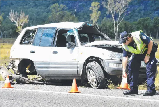  ?? AFTERMATH: A police officer at the scene of yesterday’s rollover in which a woman and a baby were trapped. Pictures: SCOTT RADFORD- CHISHOLM ??