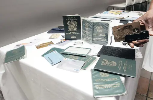  ?? PICTURE: LEON NICHOLAS ?? TOOLS OF THE TRADE: Fraudulent ID documents and passports which were confiscate­d.