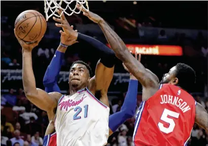  ?? LYNNE SLADKY / ASSOCIATED PRESS ?? Miami’s Hassan Whiteside drives past Philadelph­ia’s Amir Johnson during the second half Thursday in Miami. The Heat won 108-99 to increase their lead over Milwaukee in the Eastern Conference.