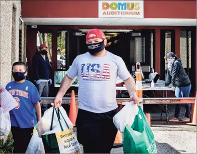  ?? File / Connecticu­t Health I-Team / ?? A man and boy leave the Domus Person to Person food pantry on Lockwood Avenue, Stamford. Person to Person works with beneficiar­ies of the Giving Fund.