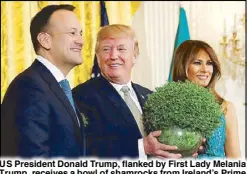  ?? REUTERS ?? US President Donald Trump, flanked by First Lady Melania Trump, receives a bowl of shamrocks from Ireland’s Prime Minister Taoiseach Leo Varadkar during a St. Patrick’s Day reception at the White House on Friday.