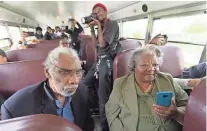  ?? MARK HOFFMAN / MILWAUKEE JOURNAL SENTINEL ?? Fred Reed (left) and Betty Harris Martin ride a bus carrying activists from the 1967-'68 open housing marches and others during a stop Saturday at Alice's Garden, 2136 N. 21st St.