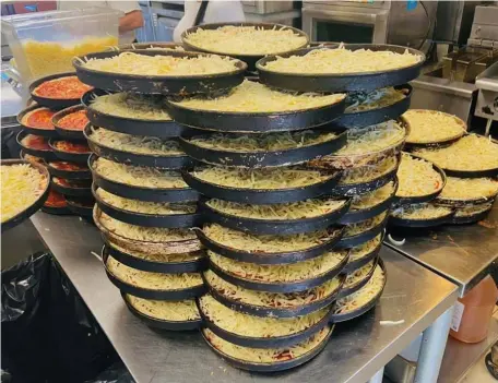 ??  ?? SUPER STACKING: Prepared bar pizza pans are ready to go at Rags Tavern in Quincy.