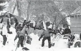  ?? Tom Bauer / Thie Missoulian via Associated Press ?? Rescuers dig franticall­y at the scene of an avalanche in Missoula’s Rattlesnak­e Valley on Friday. Three victims were rescued by neighbors and first responders.