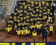  ?? ASSOCIATED PRESS FILE PHOTO ?? Michigan head coach Jim Harbaugh, bottom right, leads his team out of the Michigan Stadium tunnel before an NCAA college football game against Wisconsin in Ann Arbor, Nov. 14, 2020.