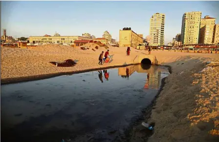  ??  ?? Polluted water: A filepic showing Palestinia­ns walking along the beach next to an outlet of a sewage treatment facility in Gaza City. — AFP