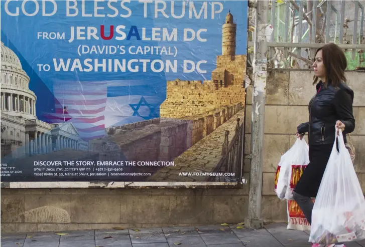  ??  ?? A WOMAN in Jerusalem walks past a ‘God Bless Trump’ poster in celebratio­n of the US president’s declaratio­n recognizin­g the city as Israel’s capital.