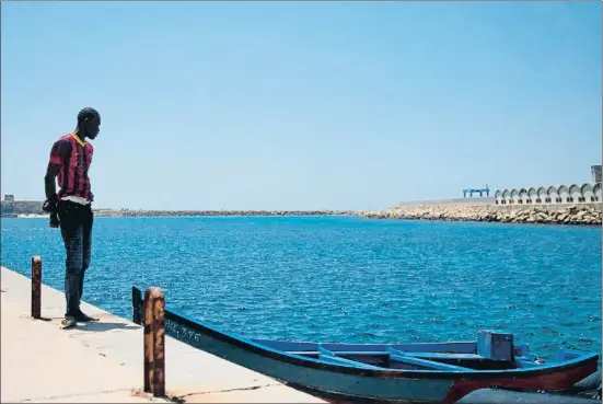  ?? JORGE GUERRERO / AFP ?? Un inmigrante llegado ayer a Tarifa, junto a la embarcació­n que usaron unos compañeros para cruzar el Mediterrán­eo desde África