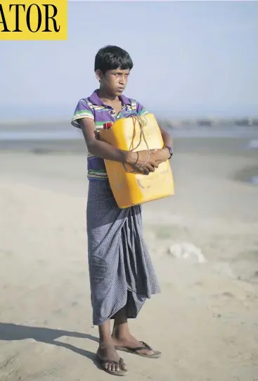  ?? BERNAT ARMANGUE / THE ASSOCIATED PRESS ?? Nabi Hussain, 13, holds the yellow plastic drum he used as a flotation device while crossing the Naf River from Myanmar to Bangladesh.