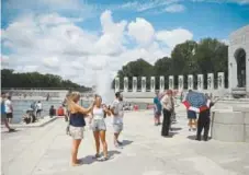  ?? Photos by Astrid Riecken, Special to The Washington Post ?? Maricar Donato carries a stars and stripes umbrella at the WWII Memorial in July.