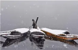  ?? — H. U. NAQASH ?? A boatman clears snow off his boat in Kashmir’s Dal Lake on Thursday. The fresh snowfall has resulted in disruption of air and road traffic for the second consecutiv­e day between Srinagar and Jammu.