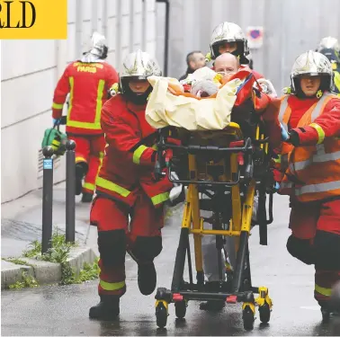  ?? ALAIN JOCARD / AFP VIA GETTY IMAGES ?? Firefighte­rs push a gurney carrying an injured person after two journalist­s were attacked in Paris on Friday near the former offices of the French satirical magazine Charlie Hebdo. Two suspects are in police custody.