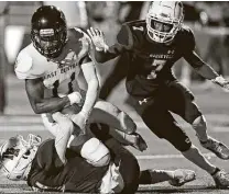  ??  ?? East Central wide receiver Reginald Stewart hangs on to the ball despite the defense of Quenten McCree and Jayden Witter (7).