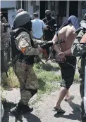  ?? OSMAN KARIMOV/ THE ASSOCIATED PRESS ?? Ukrainian troops escort men detained after a battle Friday against proRussian fighters in Mariupol, eastern Ukraine. About 100 soldiers gained back control of rebel- held positions.