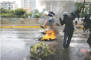  ?? ARIANA CUBILLOS/THE ASSOCIATED PRESS ?? A masked protester jumps over a burning barricade Wednesday in Caracas, Venezuela. The last 24 hours in Venezuela have been volatile.