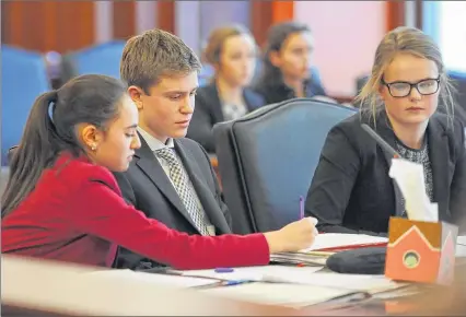 ?? MICHAEL MCLOONE / FOR THE JOURNAL SENTINEL ?? Whitefish Bay High School student Julia Campbell (left), playing an attorney, writes a note to colleagues Joseph Brousseau and Elisabeth Froiland during a mock trial regional tournament at the federal courthouse in Milwaukee on Saturday.