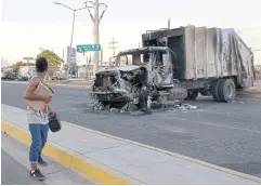 ?? PHOTOS BY AFP ?? A man passes by a burnt truck on a street during an operation to arrest Ovidio Guzman, in Culiacan, Sinaloa state, Mexico, on Thursday.